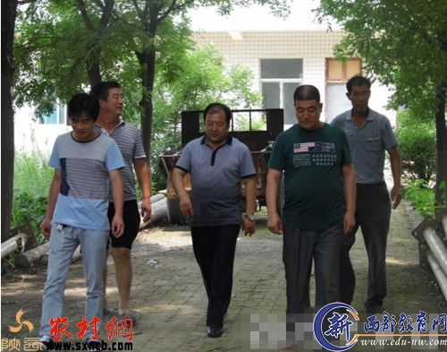 韩延军（中穿蓝衣者）与两委班子在钻井现场。
