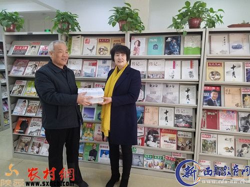 富平县图书馆馆长张丽萍（右）从《陕西文学》副主编李印功手中接过捐赠的杂志。